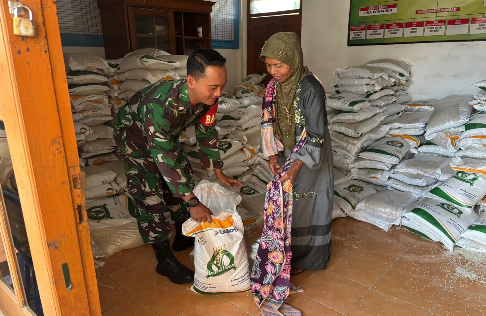Babinsa Desa Kalitengah Koramil 0808/18 Panggungrejo, Serda Andika Wahyu saat menyerah beras kepada warga